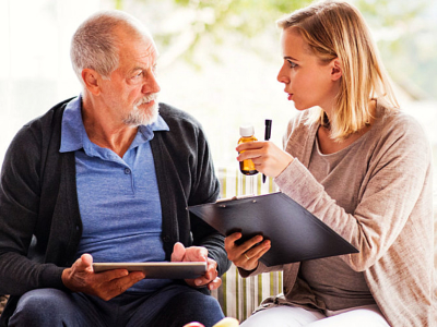 caregiver reminding elderly man about his medications