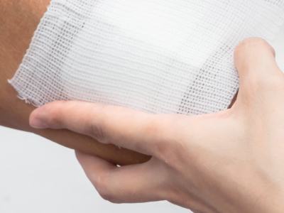 person dressing a wound of elderly person